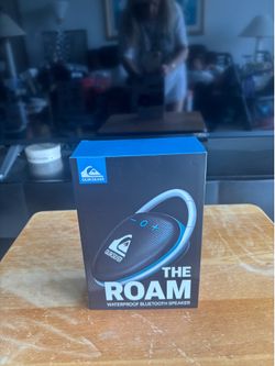 Quiksilver “The Roam” Waterproof Bluetooth Speaker (two views): Compact portable speaker with carabiner, fabric mesh, and Quiksilver branding. Markete