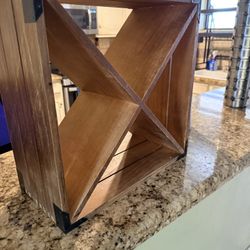 This is a small, freestanding wooden wine rack designed for a countertop or table