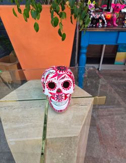 The ceramic skull is a piece of Mexican folk art designed for Day of the Dead decoration. It features intricate hand-painted patterns in red and black