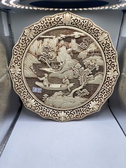 A vintage 1982 Arnart Imports "Ivory Dynasty" 3D carved resin decorative plate featuring an Asian-inspired scenic relief (such as a boat with figures,