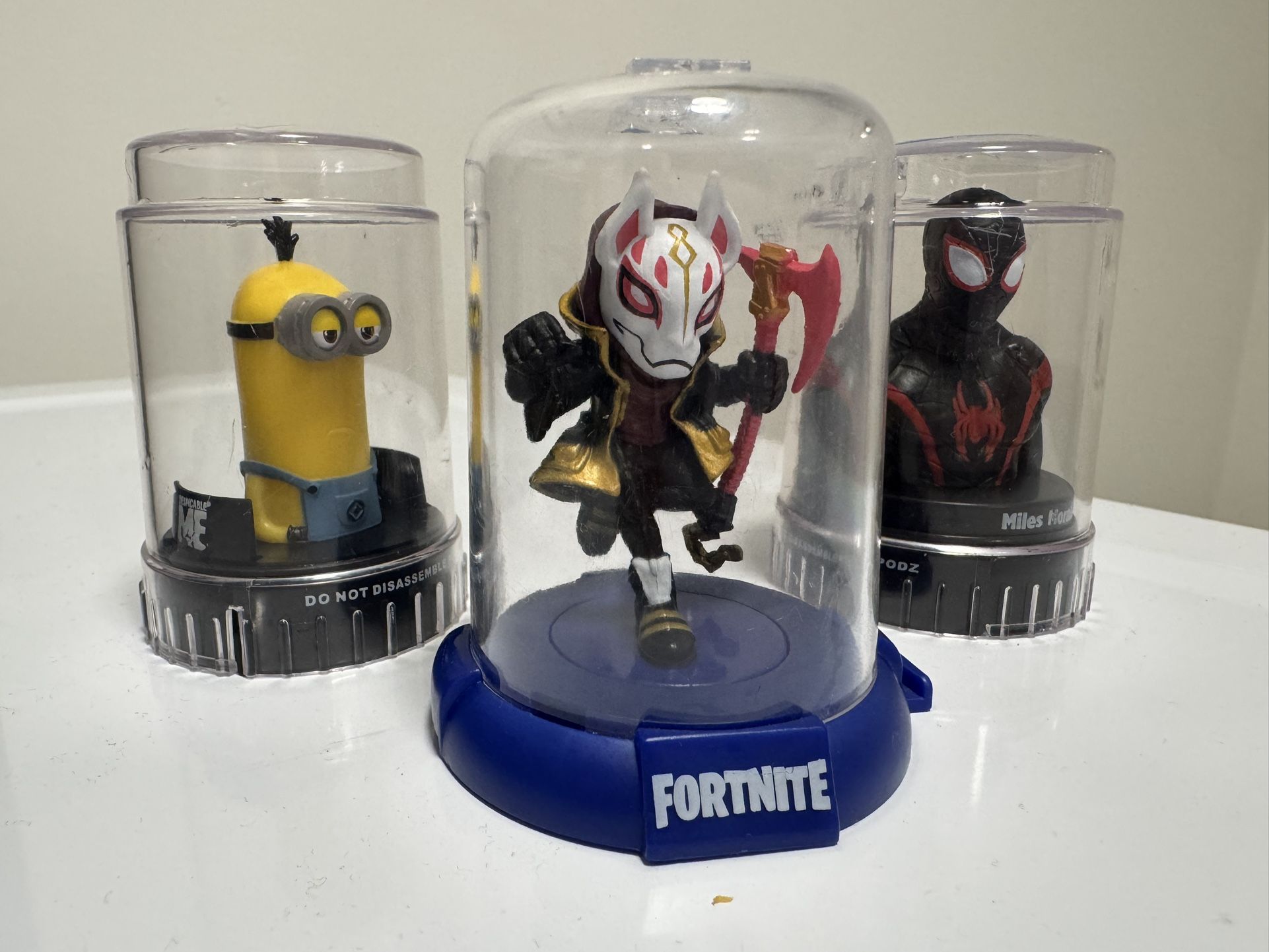 Lot of collectible figures in display capsules: Fortnite Drift, Miles Morales (PODZ), and Minion