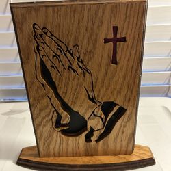 Wooden religious accent piece featuring a cutout design of praying hands and a cross
