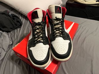 Nike Air Jordan 1 Mid sneakers in a "Gym Red" and black colorway, featuring a white leather side panel and red Swoosh