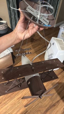 vintage-style biplane ceiling pendant light fixture featuring a wooden body, wings, and a frosted glass element designed for a child's room or themed