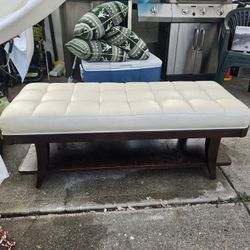 Off-white upholstered bench with a Tuffed Cushion.