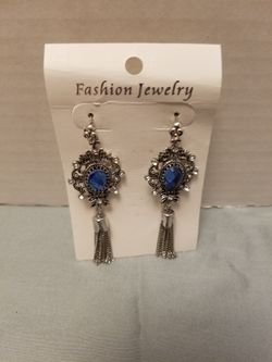 Ornate silver-tone filigree frames hold faceted blue crystals.