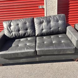 This is a set of black faux leather sofas with tufted cushions