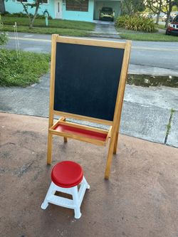 children's wooden art easel with a black chalkboard on one side and a whiteboard