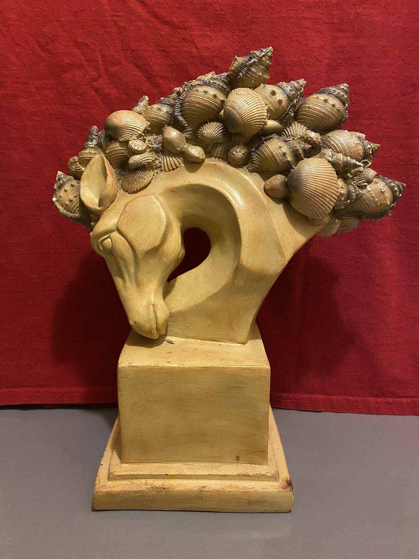 A horse head statue with a seashell mane, a decorative home accent piece.
