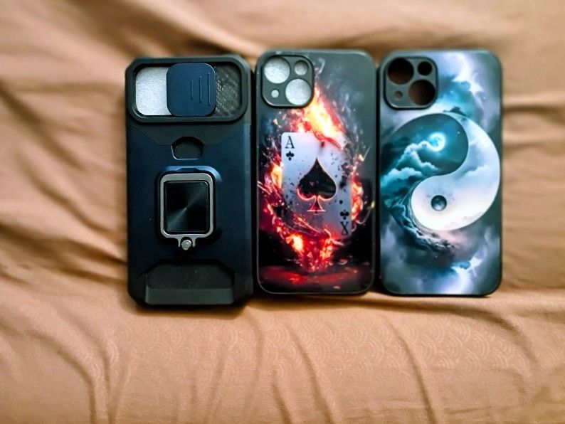 Selling a 3-case iPhone 14 Bundle. Rugged/ Heavy Duty Kickstand Case With Camera Slide, Ace Of Spades Fire Design Case, And Yin Yang Galaxy Artwork Ca