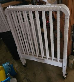Wood baby crib on four wheels, comes with mattress & pink bumper.