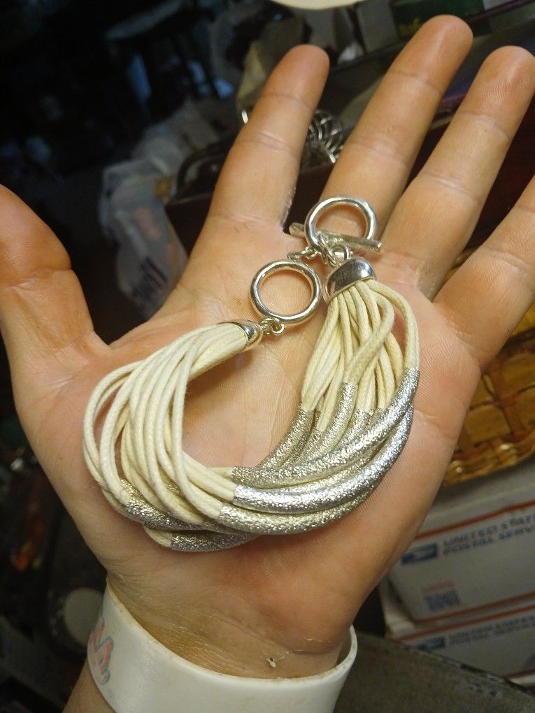 White multi-strand leather bracelet with silver-tone accents and a toggle closure.