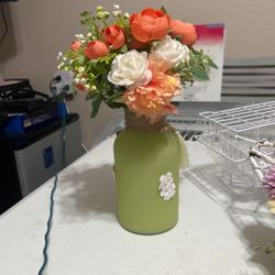 Orange and white floral arrangement in green vase