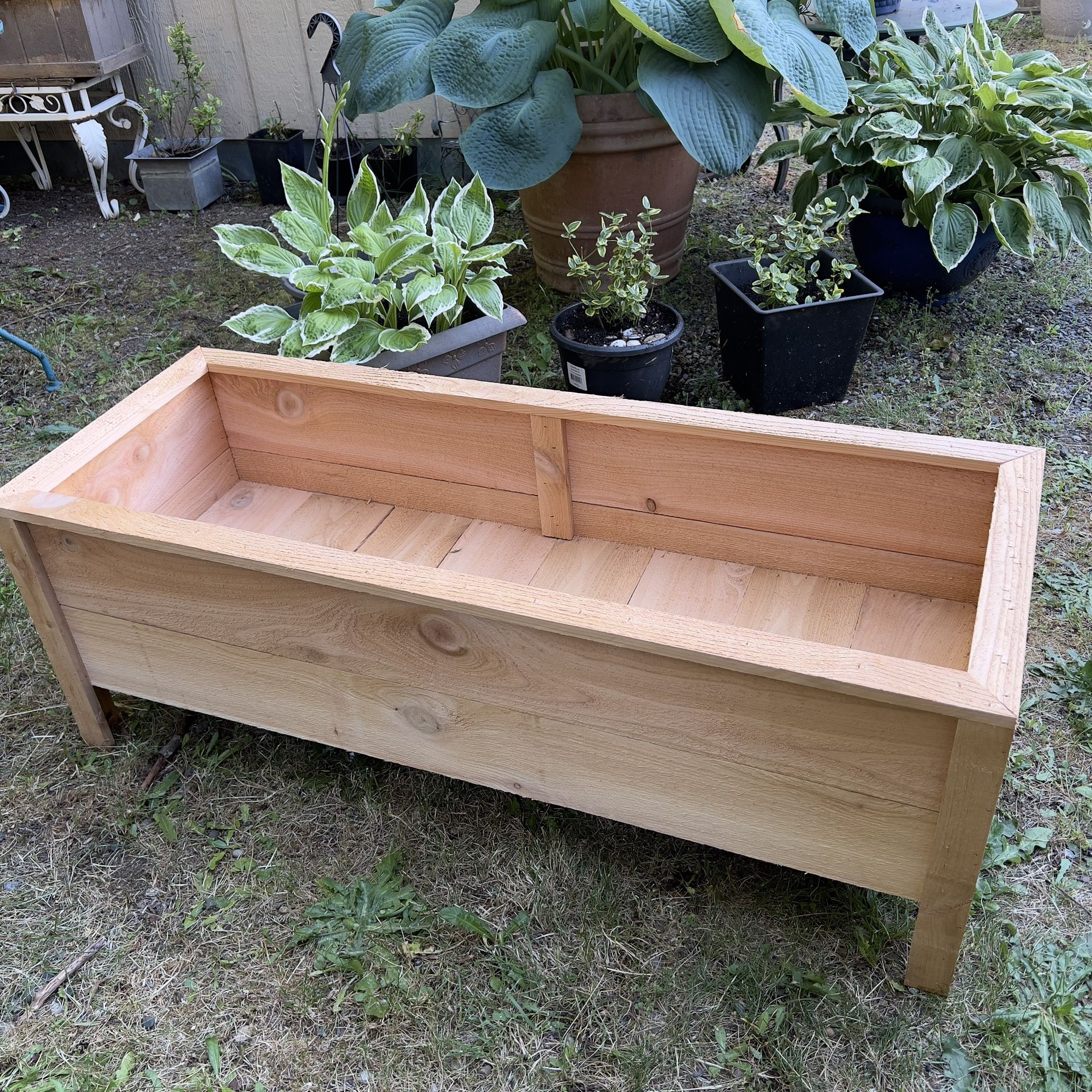 A container made of cedar wood designed for planting flowers & More.