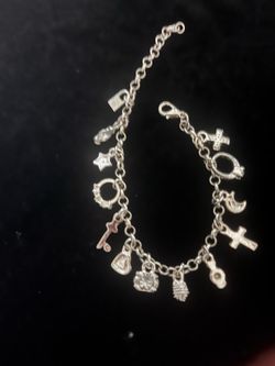 Silver charm bracelet with a lobster claw clasp. This piece has various charms including a cross, moon, star, key, lock, and ring. The chain is a clas