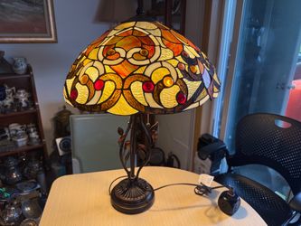 Stunning Tiffany-style table lamp features an intricate stained glass shade with vibrant yellow, orange, and red geometric and floral patterns. The da