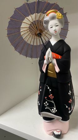 A traditional Japanese geisha or maiko kimono figurine holding an decorative umbrella (parasol).