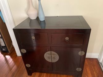 A dark wood Ming-style cabinet with brass hardware.