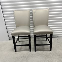 Set of bar stools upholstered in light gray with studded trim