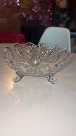 vintage clear cut footed bowl featuring a scalloped fan rim and three small curled feet.