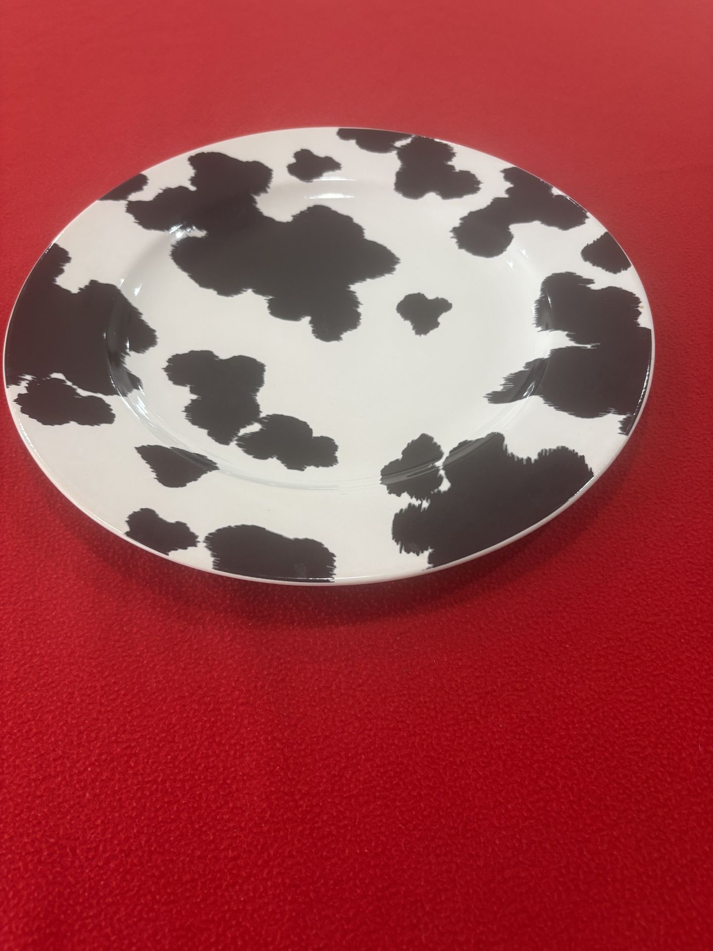 The product is a 222 Fifth cowhide large dinner plate in a farmhouse cow print design. This round plate have a diameter of 12.5 inches and is made of