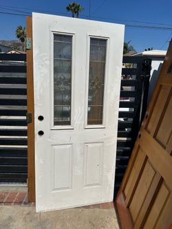 Steel entry door has two vertical decorative glass inserts with gold-toned caming. This door is painted white on one side and tan on the other. It is 