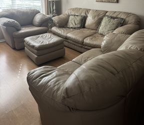 this is a set of tan leather living room furniture, including a sofa, a loveseat or chair, and an ottoman