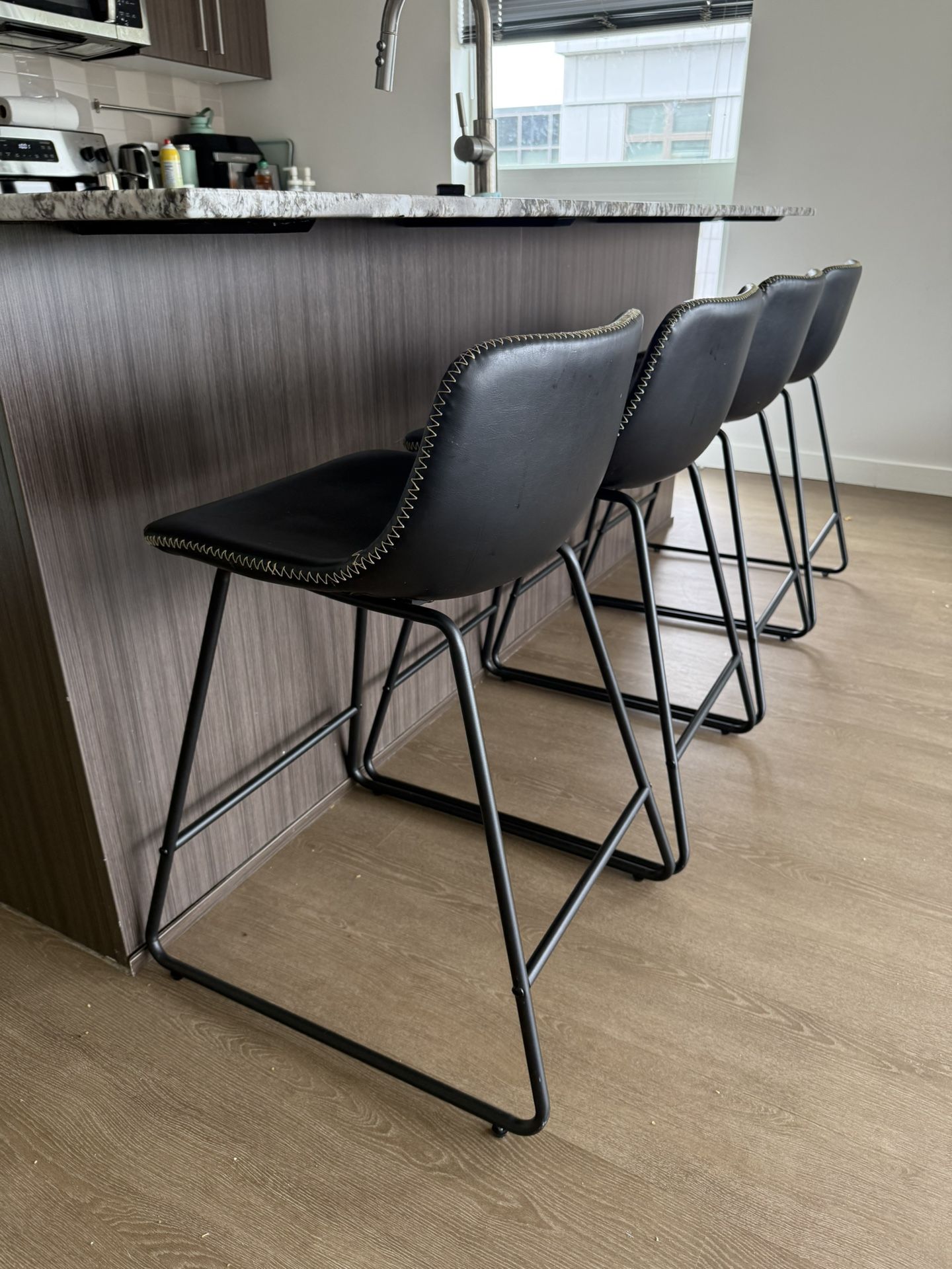 LEMBERI 26” Bar Stools – Set of 4 black faux leather stools with backrests, metal legs, and armless design. Perfect for kitchen islands