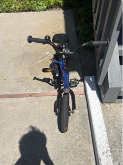 A blue kids' bicycle with BMX-style handlebars.