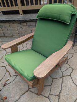 4 weather resistant acacia wood folding adirondack chairs with green cushions.