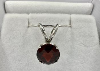 round 7mm garnet set in a sterling silver pendant with a sterling silver snake chain