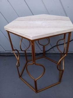Small table with gold metal legs and marble like color top.