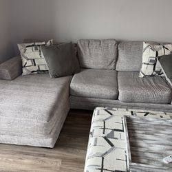 Spacious U-shaped sectional sofa in a light grey fabric. Includes a matching upholstered ottoman with a decorative tray top. Perfect for large living 