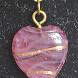 Pendant necklace made with a pink glass heart with tiny gold lines.  Chain has antiqued brass finish. Accessorized with pink ceramic beads.