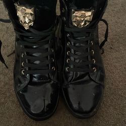 pair of black patent leather high-top sneakers with gold accents