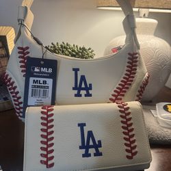 Dodgers ​The Handbag: A crescent-shaped hobo bag with a matching thick top handle. It still has the original retail tags attached, identifying the bra