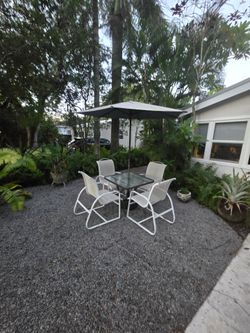 Two beautiful glass patio tables with chairs and umbrella