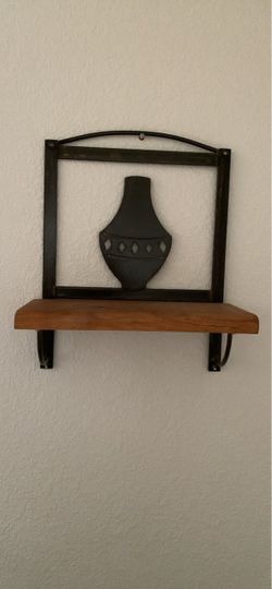 Tuscan-style wall shelf featuring a dark wrought iron frame with a decorative central vase cutout