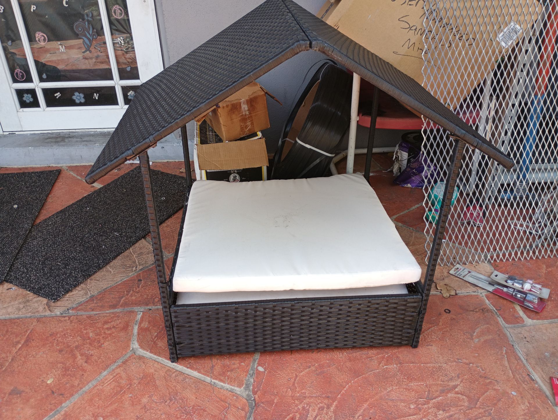 Outdoor wicker dog house or rattan pet bed with a canopy. These elevated shelters are designed for both indoor and outdoor use, featuring weather-resi