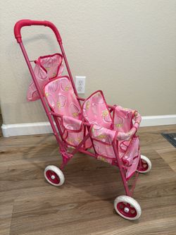 Pink double doll stroller has a strawberry pattern on the fabric