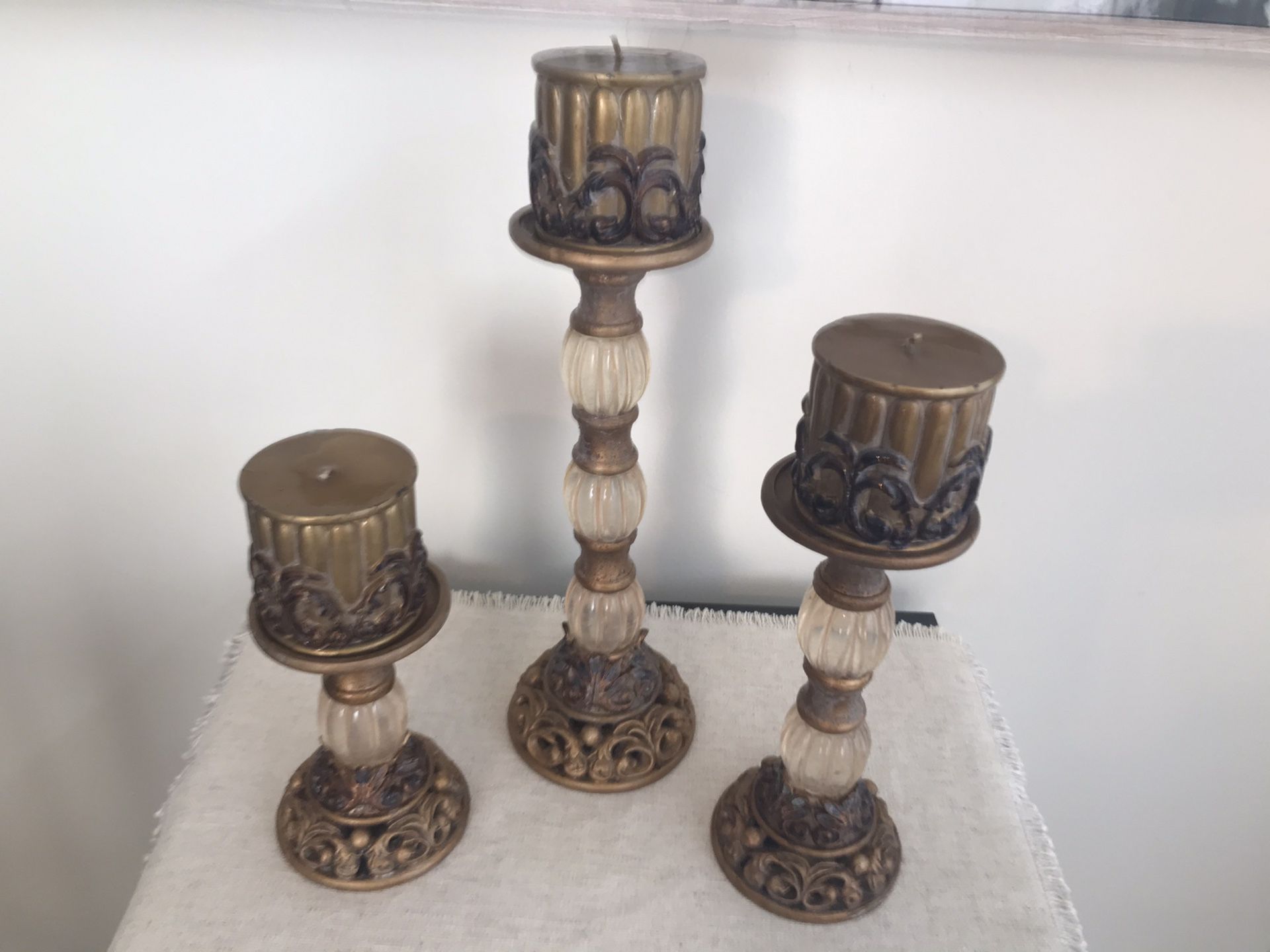 3 gold colored candle pillars/holders with candles