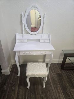 This white French provincial-style 4-drawer makeup vanity table set with an oval mirror and cushioned still