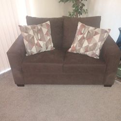 Brown Sofa Chair With Two Multi Colored Pillows 