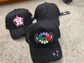 marca Innedit (modelo Muratravis Flower / Flvwer), destacando la gorra del frente con un diseño bordado de una flor colorida con cara sonriente.