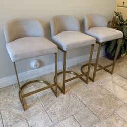 Three Restoration Hardware 1960s Rome fabric counter stool barstools. Burnished brass with off-white fabric. 