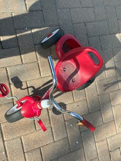 This is a classic red Radio Flyer tricycle (likely the standard Classic model), featuring a bright red plastic frame, seat, and fender with chrome han