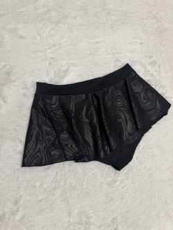 Black skirted shorts with a subtle swirl texture. Designed for comfort with a soft elastic waistband. Versatile piece that pairs well with athletic or