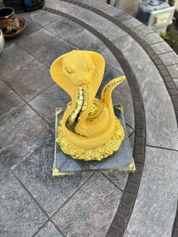 gold-tone cobra statue on a glass base, feng shui symbol of protection and prosperity