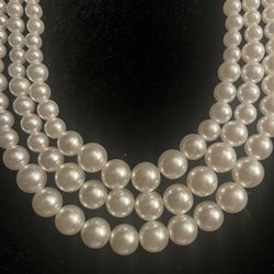 Elegant multi-strand pearl necklace. Has three strands. Pearls are a pretty white/cream color. Bottom strand has larger pearls, top strands smaller on