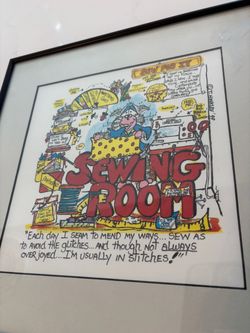 framed humorous cartoon art print titled "Sewing Room" by T. Hinkley ('99) featuring a chaotic sewing space with witty wordplay. 12 x 12.